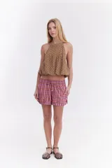 Blusa crop estilo halter con diseño abullonado en la parte inferior, confeccionada en lino con estampado de rayas verticales sutiles.