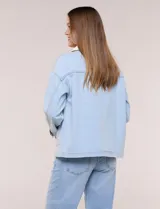 Campera de denim blanco de corte holgado con hombros caídos, cuello con solapa en contraste de color celeste, cierre frontal con botones metálicos y bolsillos delanteros con solapa.