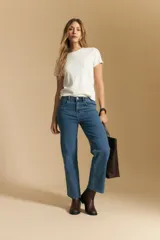 Jean de corte recto y tiro medio, confeccionado en denim elastizado. Presenta un diseño clásico con cinco bolsillos, cierre frontal con botón y ruedo desflecado.