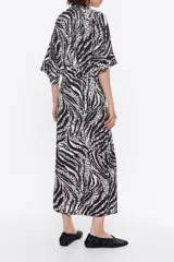 Vestido midi de viscosa con estampado abstracto en blanco y negro, escote en pico con lazo y manga corta.