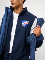 Parka larga con bloques de color azul, capucha y chaleco desmontable de polar azul marino con escudo del Club Nacional de Football bordado en el pecho.