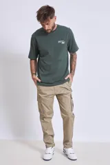 Remera de algodón color verde oscuro, de corte holgado, con cuello redondo y pequeño estampado gráfico en el pecho.