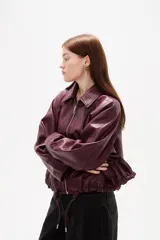 Campera de eco-cuero en color bordó, con cuello camisero, cierre frontal con cremallera y cordones ajustables en el ruedo.