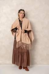 Ruana abierta de color beige, confeccionada en tejido de punto con terminación de flecos en el ruedo.