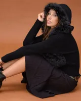 Campera de diseño combinado con cuerpo en textura de piel sintética y mangas tejidas. Presenta una capucha amplia con borde de pelo sintético y cierre frontal.