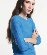 Blusa de punto color azul, con textura ondulada, cuello redondo y mangas largas. Presenta terminaciones en rib en puños y ruedo.