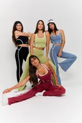 Conjunto deportivo compuesto por un top corto y un pantalón largo, ambos de color bordó con detalles de líneas blancas en los costados. El top presenta cuello redondo y el logo 'bk.' estampado en el frente.