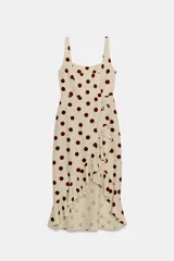 Vestido midi de mezcla de lino y viscosa en color beige con estampado de lunares bordó. Cuenta con escote recto, tirantes anchos y un volante lateral en cascada que recorre el frente hasta el bajo asimétrico.