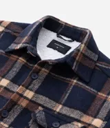 Campera tipo trucker de franela con estampado de cuadros, cuello inglés, cierre frontal con botones, bolsillos con solapa en el pecho y bolsillos laterales. Cuenta con forro interno de sherpa para mayor calidez.