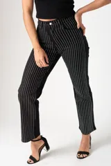 Jeans de corte recto en color negro, con diseño de rayas verticales formadas por aplicaciones de strass plateado. Presenta tiro medio-alto, cierre frontal con botón y bolsillos laterales.