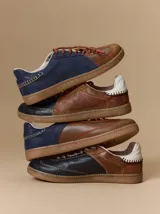 Championes urbanos de cuero con diseño de paneles en combinación de colores, costuras decorativas a la vista y suela de goma. Cuentan con cordones intercambiables y logo de la marca bordado en el lateral.