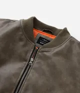 Campera bomber de poliuretano con acabado efecto cuero, cuello redondo, cierre frontal con cremallera, bolsillos delanteros y bolsillo utilitario en la manga. Presenta puños y ruedo elásticos, con forro interior en contraste.