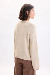 Sweater de punto de cinta en color crudo, de manga larga, con cuello redondo y diseño holgado.