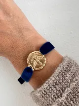 Pulsera con medalla dorada con la imagen del Espíritu Santo y cinta de terciopelo azul.