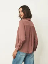 Camisa de manga larga con cuello clásico y cierre frontal de botones, confeccionada en tela con acabado satinado.