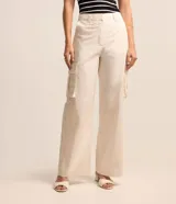 Pantalón recto color crema, confeccionado en tricolina, con cintura tipo sastreria, trabillas, cierre por botón y cremallera, y bolsillos cargo laterales.