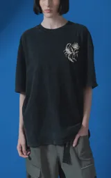 Remera de algodón premium con efecto nevado, corte oversize y cuello redondo. Presenta una estampa gráfica en la espalda con motivos de escorpión, rosa y tipografía en color crema.