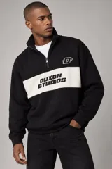 Buzo negro de algodón sin friza, con cuello alto, cierre frontal parcial y una franja blanca horizontal en el pecho que incluye el texto "Duxon Studios" en negro, además de un logo bordado en el pecho.