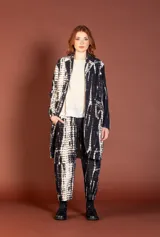 Chaqueta larga de silueta amplia, con estampado tie-dye en blanco y negro, solapas de traje y cierre frontal con botones.