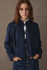 Chaqueta de pana azul marino con cuello mao, cierre frontal de botones dorados y mangas largas con puños rectos. Presenta un diseño holgado y estructurado.