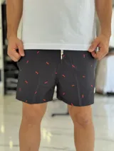 Short de baño negro con pequeño estampado rojo repetido y cordón ajustable en la cintura.