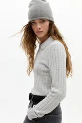 Sweater de punto gris, con diseño de ochos, cuello polo y cierre frontal parcial con botones. De manga larga y calce clásico.