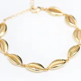 Pulsera dorada con eslabones de cadena y dijes de caracoles.