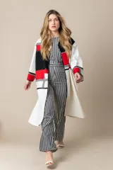 Túnica larga color marfil con vivos negros de satén, bolsillos laterales y diseño geométrico con bloques de color rojo y negro.