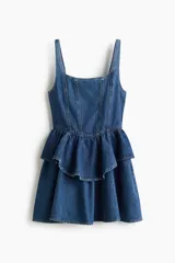 Vestido corto de denim azul con tirantes anchos, escote cuadrado, cuerpo entallado con costuras visibles y falda acampanada con doble volado en la cintura.