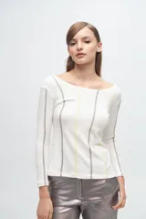 Remera de manga larga en color blanco con diseño de líneas verticales bordadas en tonos gris y amarillo. Presenta un escote amplio y corte ajustado al cuerpo.