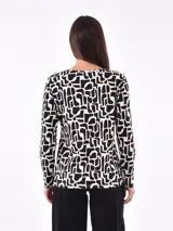 Remera blanca de manga larga con cuello redondo y detalle de botones dorados en los hombros.