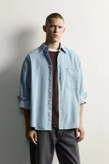 Camisa regular fit de denim de algodón con efecto lavado, cuello solapa y manga larga con puño abotonado. Tiene un bolsillo de parche en el pecho con detalle bordado a contraste y cierre frontal con botonadura.
