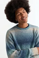 Sweater de tejido de punto con diseño degradé en tonos azules y beige, de corte holgado, cuello redondo y mangas largas.