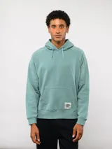 Canguro de felpa color verde menta, con capucha, bolsillo canguro frontal y etiqueta del logo Umbro en la parte delantera.