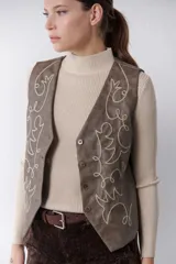 Chaleco marrón de simil cuero con bordado en color crema, cuello en V y cierre frontal con botones.