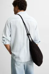 Bolso tipo shopper de tejido macramé marrón oscuro, con forma trapezoidal y asas de hombro trenzadas.