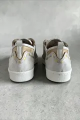 Championes de cuero de diseño artesanal, combinados en tonos plateado, dorado y natural. Presentan detalles pintados a mano por Carolina De Cunto, cordones al tono, suela de goma blanca y aplique metálico con logo en el lateral.