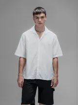 Camisa blanca de manga corta, con cuello abierto y calce oversize. Confeccionada en algodón bordado tipo broderie con diseño floral.