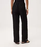 Pantalón de tricot negro con corte wide leg, transparencia delicada y bordado abstracto en relieve. Cuenta con cintura elástica y caída fluida.