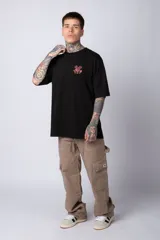 Remera negra de algodón de corte oversize, con mangas cortas y cuello redondo. Estampado pequeño en el frente y diseño grande en la espalda con Mickey Mouse y caracteres orientales en tonos rojizos.