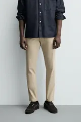 Pantalón chino de corte ajustado, color beige, con bolsillos laterales y bolsillos traseros de vivo. Cuenta con cierre frontal de cremallera y botón.