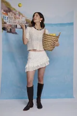Falda mini de crochet color crudo, con diseño de volados en diagonal que aportan movimiento y textura artesanal.