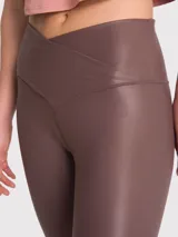 Calza deportiva de tiro alto con cintura en forma de V, confeccionada en tela brillante con acabado efecto cuero. Presenta un diseño ajustado de largo al tobillo.