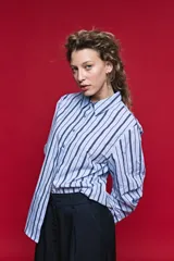 Camisa de algodón celeste con rayas verticales azul marino y marrón, cuello camisero clásico y cierre frontal de botones nacarados.