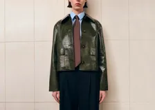 Chaqueta verde oscuro de poliuretano con acabado efecto cocodrilo, corte recto, bolsillos con solapa en el frente y cierre de botones.