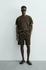 Bermuda de hombre color verde oscuro, de corte relajado y tiro medio. Confeccionada en tejido texturado, presenta cintura elástica con cordón de ajuste interno y bolsillos laterales y trasero de vivo.