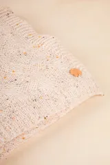 Bufanda rectangular tejida color gris con pequeños puntos de color.