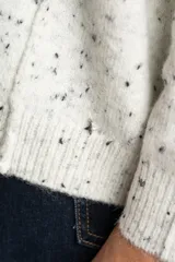 Sweater de punto color gris melange con efecto tweed o salpicado en negro, de calce oversize y cuello redondo.