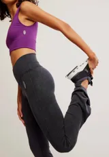 Calza de tiro alto con diseño acampanado en el ruedo, confeccionada en tejido acanalado de color negro. Presenta una costura en forma de V en la cintura y un pequeño logo bordado en la cadera.