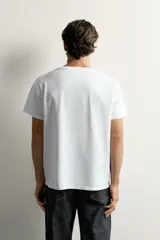 Camiseta blanca de corte relajado, con cuello en V y mangas cortas.